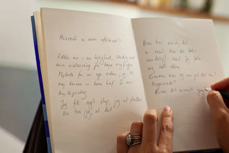 Åben notesbog med håndskrevne ord, der symboliserer anonym deling af personlige oplevelser.