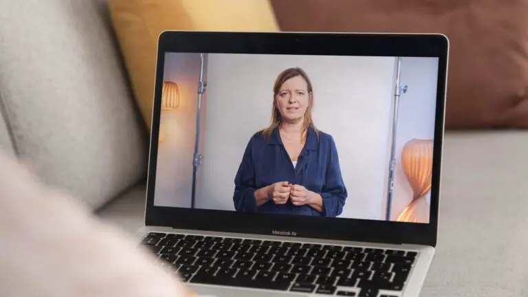 Bærbar computer placeret i en sofa i hjemlige omgivelser, hvor der på skærmen ses en afspillende video med en af LULUs gruppeledere og rådgivere, der formidler faglig viden om vold.